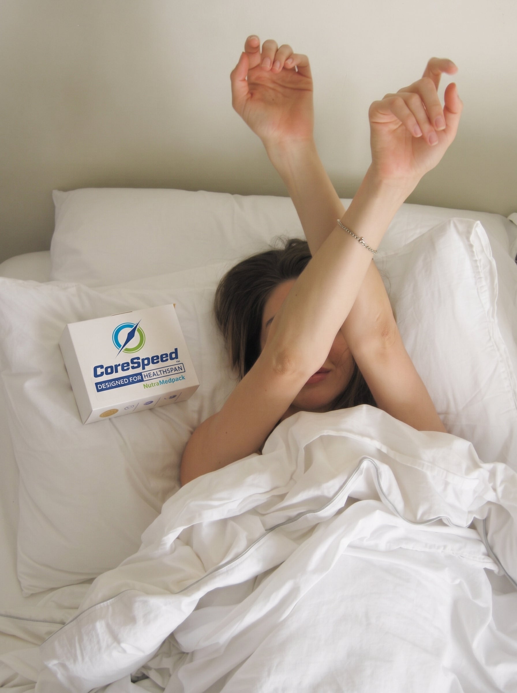 Woman resting in bed beside a CoreSpeed NutraMedpack box